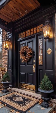 a black front door with two potted plants on the steps and lights above it