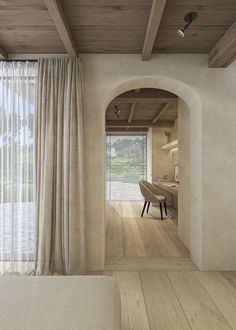 the interior of a bedroom with wood floors and white curtains on the windowsills