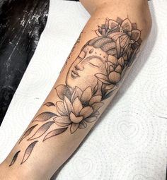 a woman's arm with flowers on it and a buddha face in the middle