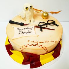 a birthday cake with an owl and scissors on it's top is decorated to look like harry potter