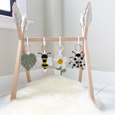 a baby crib with three little bugs hanging from it's sides and a white rug on the floor