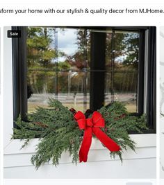 a christmas wreath sitting on top of a window sill next to a red bow