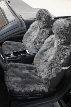 the interior of a car with grey fur and black leather seats, including two steering wheel covers