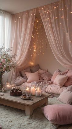 a living room filled with lots of pink furniture and lights hanging from the ceiling above