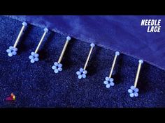 four blue flowers are lined up on a purple background with the words needle lace written above them