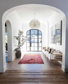 a living room with wood flooring and arched doorway leading into the dining area that has a chandelier hanging from the ceiling