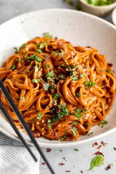 a white bowl filled with noodles and garnished with parsley