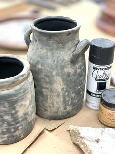 two vases sitting on top of a table next to some paint and other items