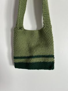 a crocheted bag hanging on the wall with a hook in it's mouth