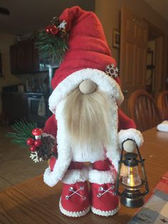 a stuffed santa clause is sitting on a table next to a lantern and christmas decorations