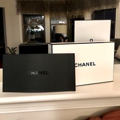 three chanel boxes sitting on top of a white counter next to a couch in a living room