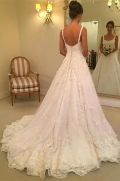 a woman standing in front of a mirror wearing a wedding dress