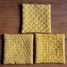 three pieces of yellow fabric sitting on top of a wooden table