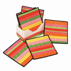 four square coasters with different colored stripes on them, one in the center and one in the middle