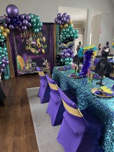 the table is set with purple and green balloons, mermaid decorations, and streamers