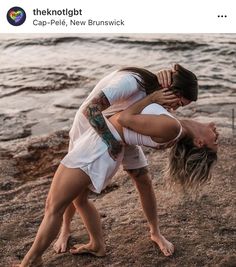 a man and woman standing on top of each other in front of the ocean with their arms around each other