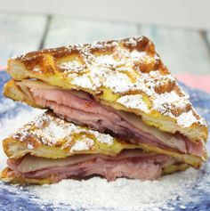 a blue plate topped with two slices of ham and cheese sandwich on top of powdered sugar