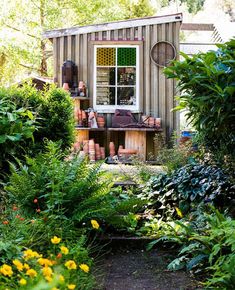 an outhouse is surrounded by plants and flowers