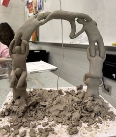 two clay sculptures sitting on top of a table in front of a person working on something