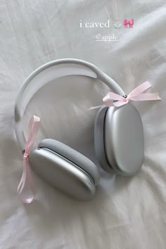 a pair of headphones laying on top of a white sheet with a pink ribbon