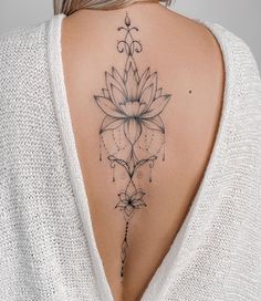 the back of a woman's neck with a flower tattoo on it