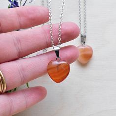 This necklace is made from a carnelian stone which has been cut into a puffy heart. The stone hangs from a silver plated chain. You can choose the length of the necklace you prefer. You will get a necklace at random. Please note that all necklaces are handmade and may differ from the pictured. The picture shows multiple necklaces. You will receive one necklace with one pendant. Ewelina Pas Jewelry Gift Carnelian Crystal Necklace In Orange, Heart-shaped Orange Jewelry For Gift, Orange Carnelian Crystal Necklace As Gift, Orange Carnelian Crystal Necklace For Gift, Orange Carnelian Crystal Necklace Gift, Orange Heart-shaped Jewelry Gift, Orange Heart Beads Jewelry For Gift, Heart-shaped Orange Necklace For Gift, Orange Jewelry With Heart Beads For Gifts