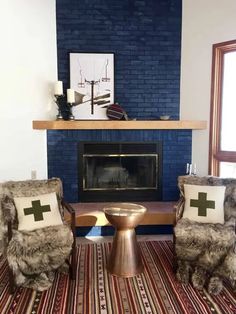 a living room with two chairs and a table in front of a fire place that has a cross on it