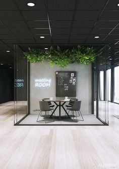 a meeting room with glass walls and plants growing on the wall