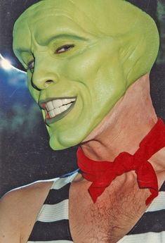 a man wearing a green mask with a red bow around his neck and striped shirt