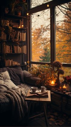 a living room filled with furniture next to a window covered in fall leaves and candles