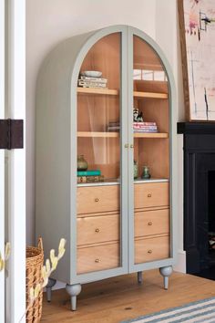 an arch - shaped cabinet with drawers in the middle of a room next to a fireplace