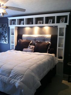 a large bed sitting in the middle of a bedroom next to a wall mounted bookcase