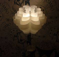 a lamp that is on top of a table in front of a wallpapered wall