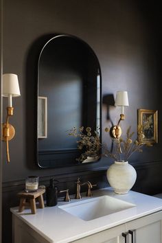 a white sink sitting under a large mirror next to a wall mounted faucet