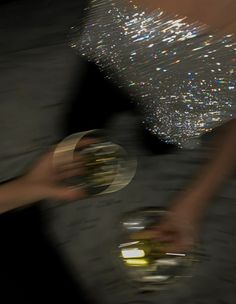 two people are holding wine glasses with sparkling bubbles on the top and bottom of them