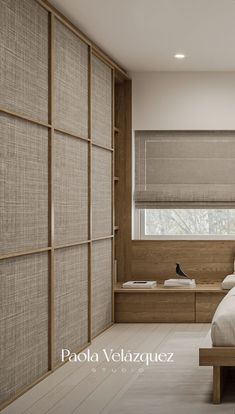 a bed sitting under a window in a bedroom next to a wooden shelf filled with towels