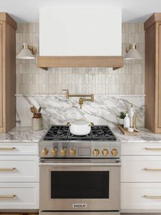 a stove top oven sitting inside of a kitchen next to white cupboards and counter tops