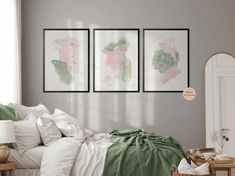 three paintings hang on the wall above a bed in a room with white sheets and pillows