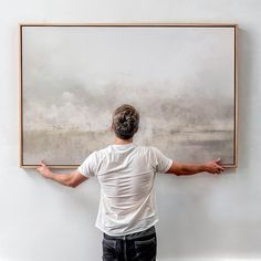 a man standing in front of a painting with his arms spread out to the side