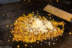 corn kernels are scattered on top of a black surface next to a grater