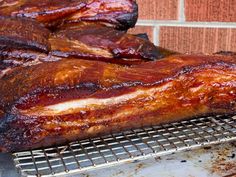 ribs on a grill being grilled in front of a brick wall