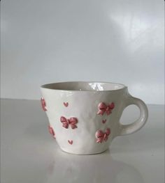 a white cup with pink flowers and hearts painted on the inside is sitting on a table