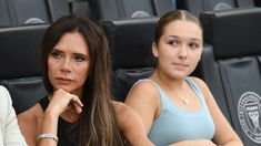 two women sitting next to each other in front of a black chair at a tennis match