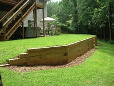 a wooden deck in the middle of a yard with stairs leading up to an upper level