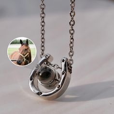 a horse's head is attached to a silver chain with a camera in the middle