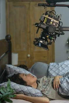 a woman laying in bed with a camera attached to her head and on top of the bed