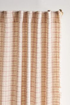 a close up of a curtain on a white wall with an orange and brown checkered pattern