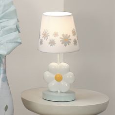 a white lamp sitting on top of a table next to a vase with flowers in it