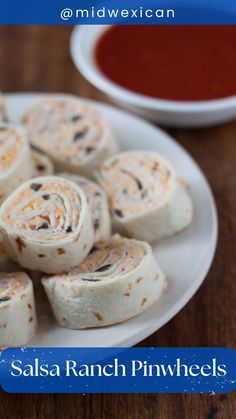 a white plate topped with rolls next to a bowl of sauce