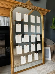 a gold framed mirror sitting on top of a floor next to a fireplace covered in notes